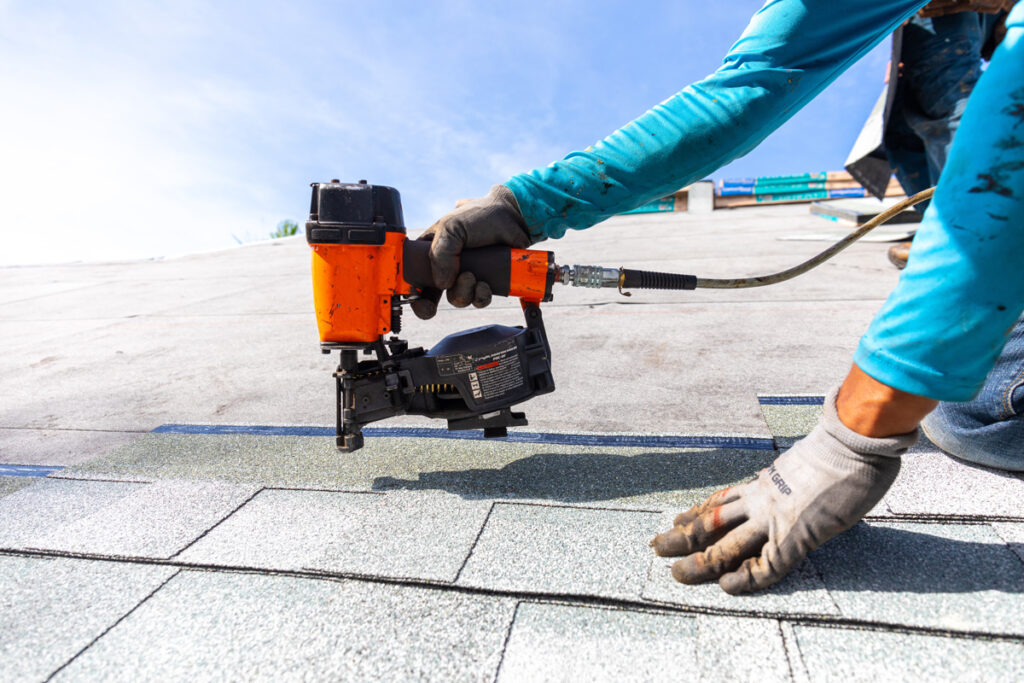 A person using an orange and black tool for a new roof installation in Euclid.