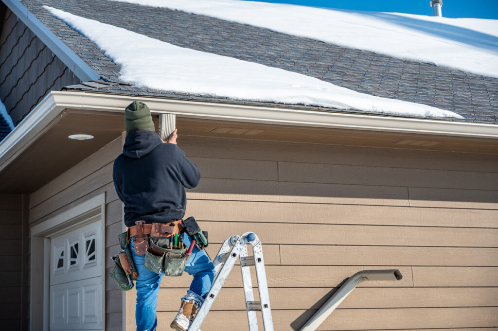 A person on a ladder performing maintenance on a gutter at a Euclid home.